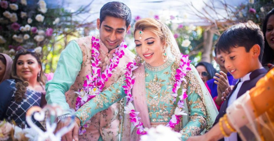 Image of A Beautiful Bride & Groom Cutting The Wedding Cake - Representing The Candid Memories Of Wedding Ceremony.